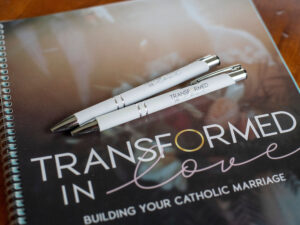 Two Transformed in Love pens sitting on top of a workbook