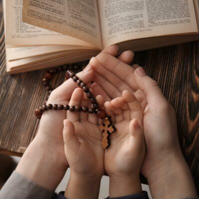 A woman and child's hands holding a rosary